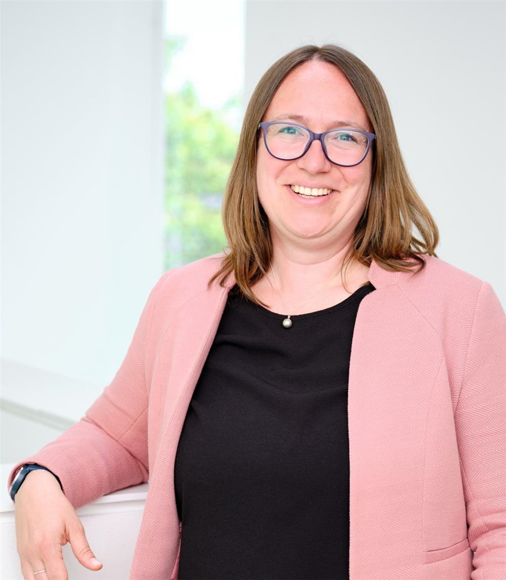 Foto einer Frau mit Brille, die freundlich lächelt